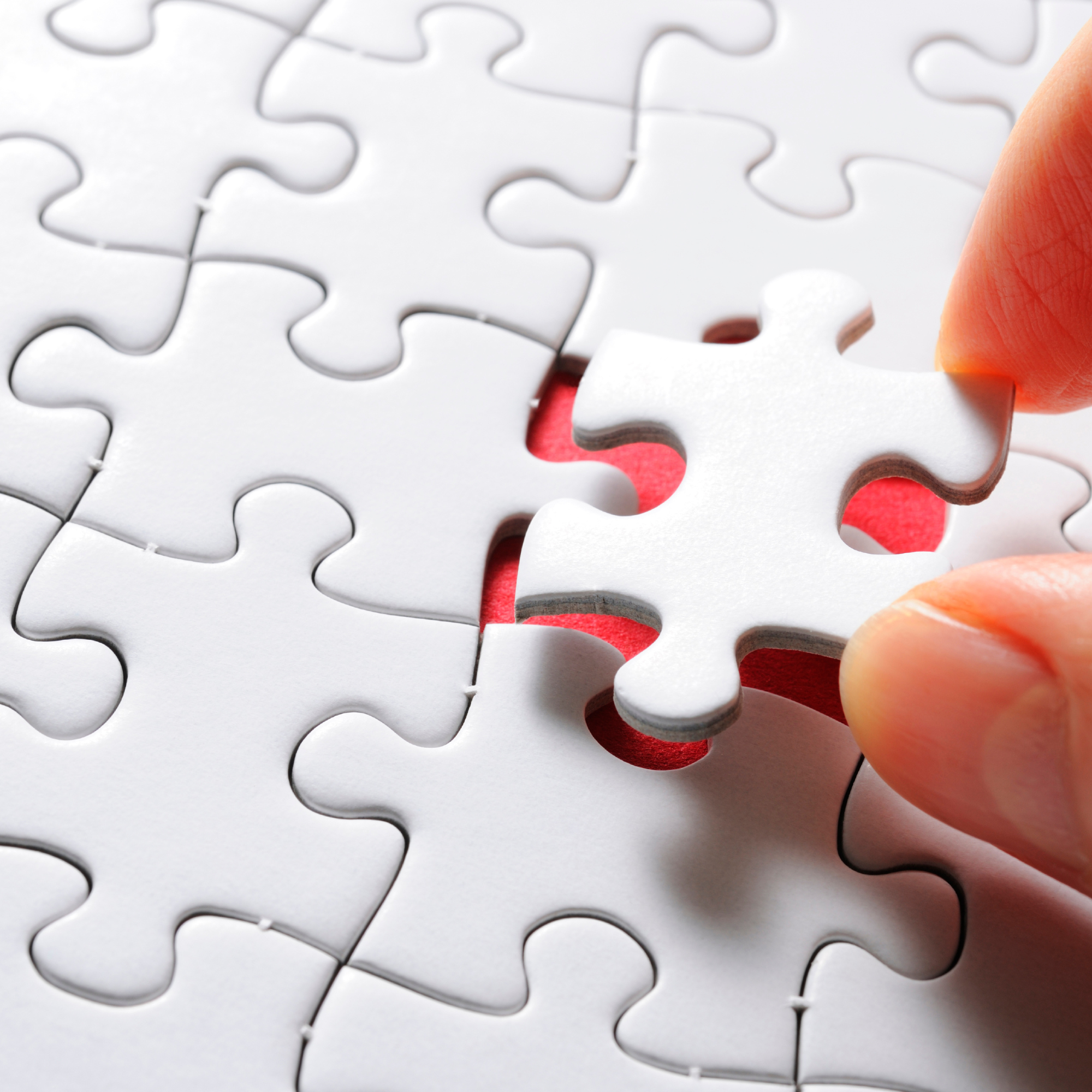Hand completing a puzzle with a missing piece